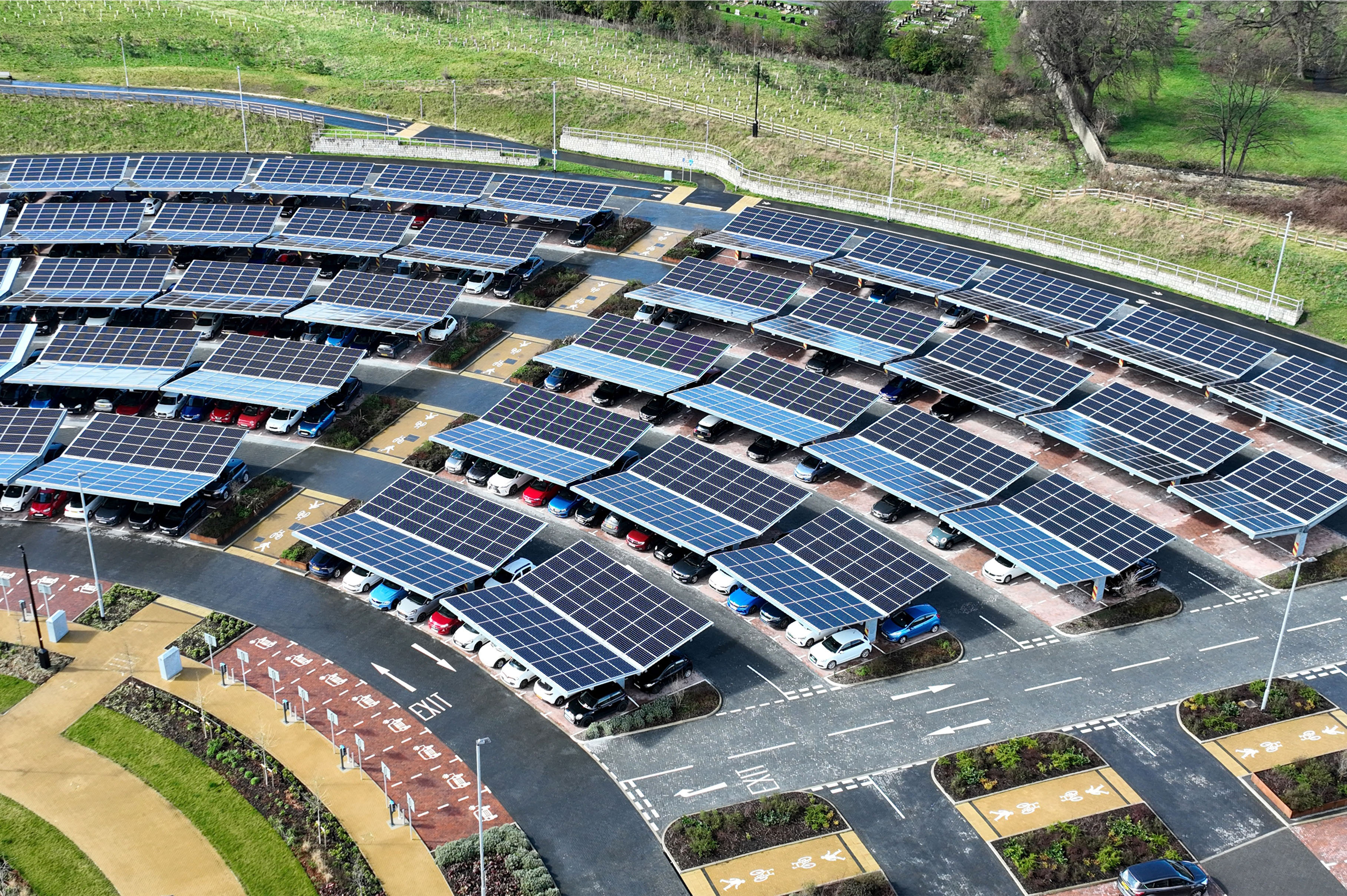Rows of solar panels installed over a car park in a landscaped area — showcasing renewable energy and sustainable infrastructure.